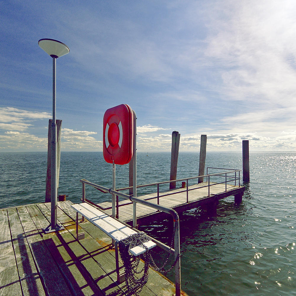 Hafenmole mit Anlegepfählen und Blick aufs Meer